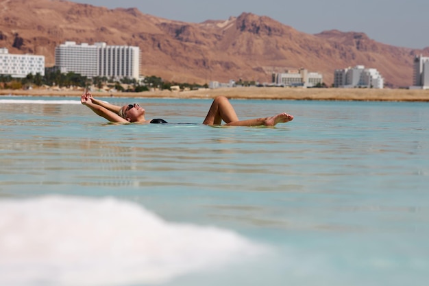 Sexy blonde vrouw in een zwart zwempak ligt aan de Dode Zee Israël hoge kwaliteit foto