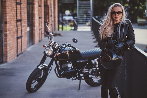 Sexy blonde vrouw poseert voor fotograaf terwijl ze naast haar fiets staat.