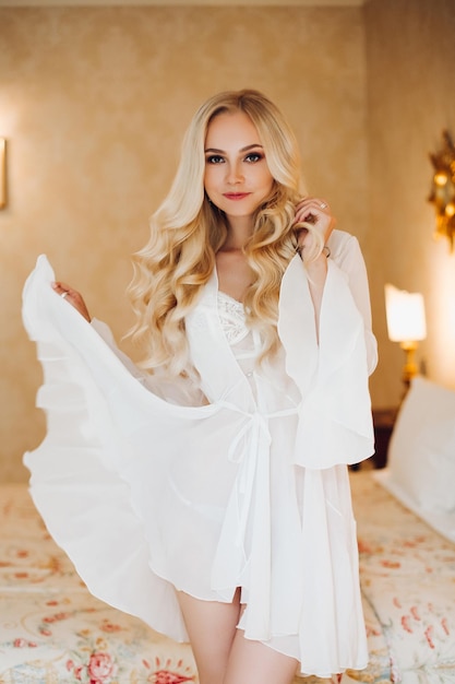 Сексуальная невеста-блондинка в белом кружевном нижнем белье раздевается