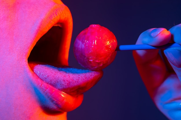 Фото Символ сексуальный минет. сексуальный рот, облизывающий леденец на палочке, красные женские глянцевые губы и розовые леденцы на палочке.