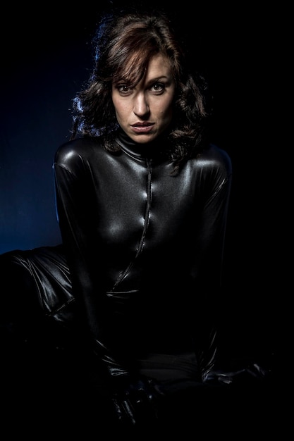 Bruna sexy in costume in lattice nero, colpo di moda di una donna in nero lucido