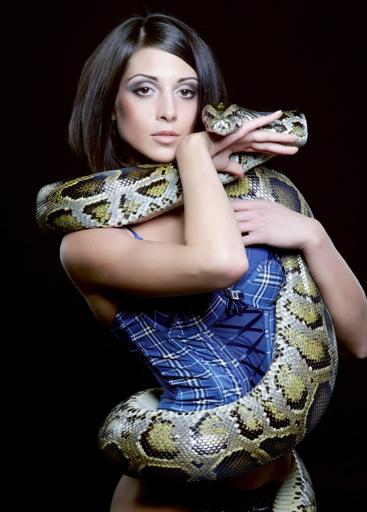 Premium Photo | Sexy brunette holding python over black