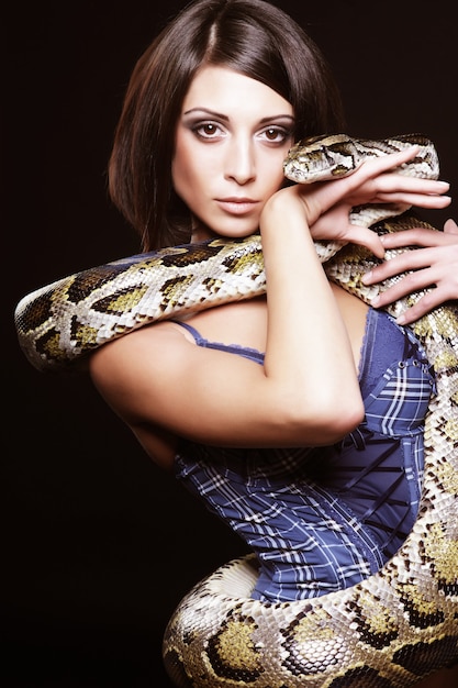 Premium Photo | Sexy brunette holding python over black