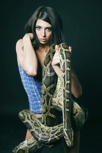 Photo sexy brunette holding python over black