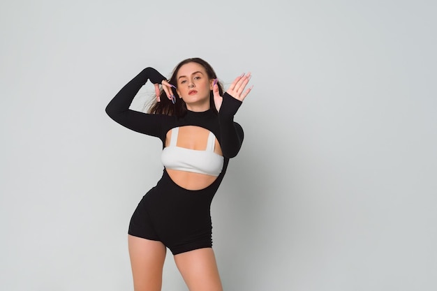 Sexy brunette in zwarte dans bodysuit en witte top met lange nagels poseert dansen toont haar handpalm