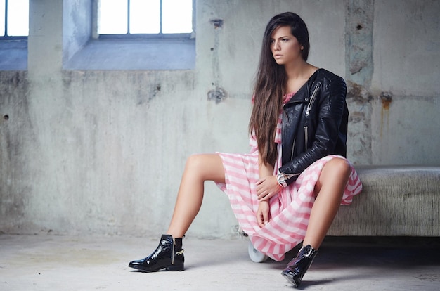 Sexy brunette in pink dress and leather jacket posing on camera.