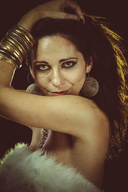 Sexy brunette woman wearing white fur and gold jewelry