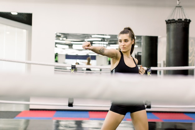 Sexy Caucasian female boxer standing in the boxing ring at gym