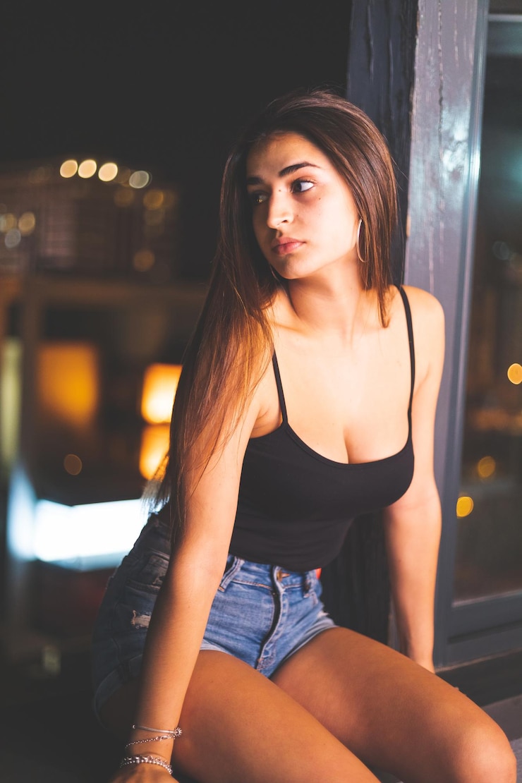 夜のバルコニーの端に黒いトップとショートパンツを持つセクシーな白人女性。マドリッド、スペイン。