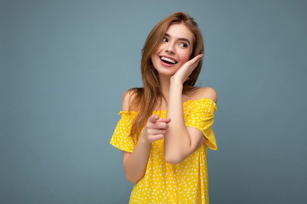 Sexy charming smiling good looking young blonde woman wearing stylish yellow summer dress standing