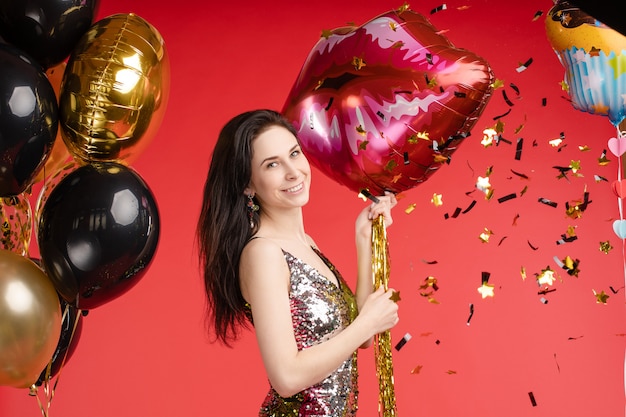 Sexy elegant brunette in beautiful sparkling dress with air balloons.