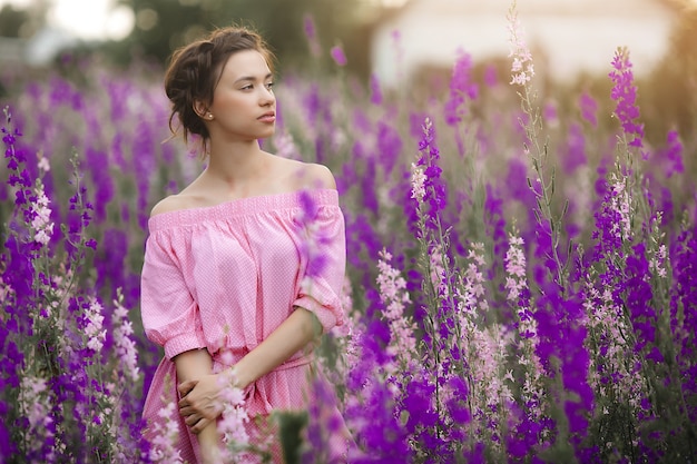 花の牧草地でセクシーなエレガントな女性。屋外の美しい女性。自由の概念