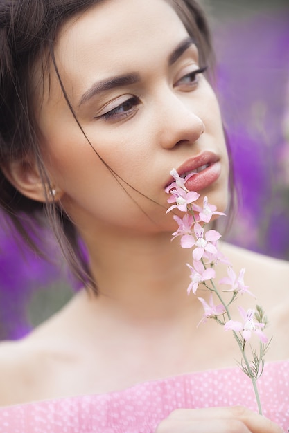 Sexy elegant woman on the meadow of flowers. Beautiful female outdoors. Freedom concept