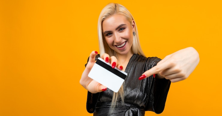 Photo sexy european girl holds a credit card with a mockup for shopping on a yellow.