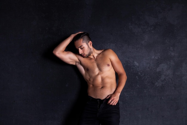 Sexy and expressive shirtless male model flirting against black background