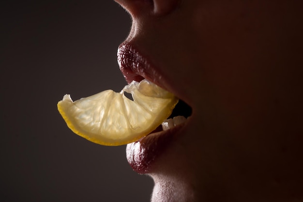 Frutta sexy primo piano labbra con limoni vitamina c concetto di rinfresco estivo ora del tè ragazza con fetta di limone macro primo piano delle labbra della bocca che masticano agrumi gialli