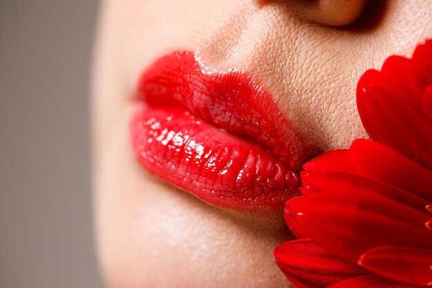 Sexy full female lips with red lipstick on the background of a flower aesthetic medicine services