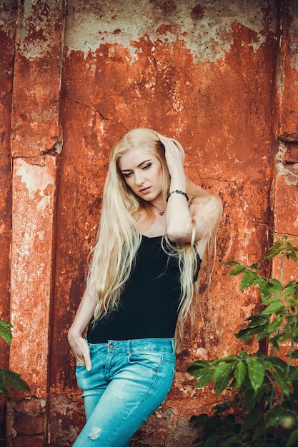 Sexy girl in denim pants and a black tshirt on a background of red textures