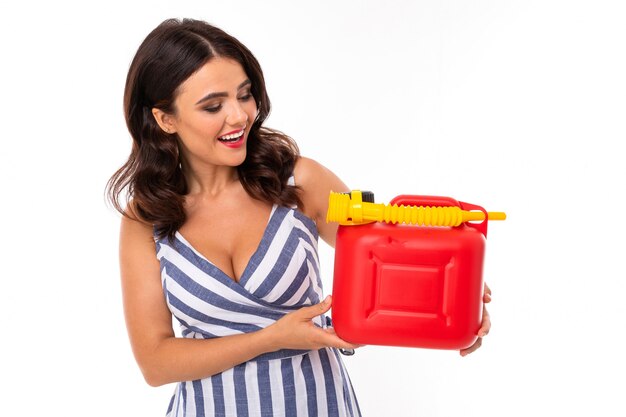 Sexy girl in a dress holds a red canister with fuel gasoline on white with copy space