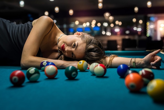 Sexy girl lies on the snooker table among the balls billiard game lifestyle