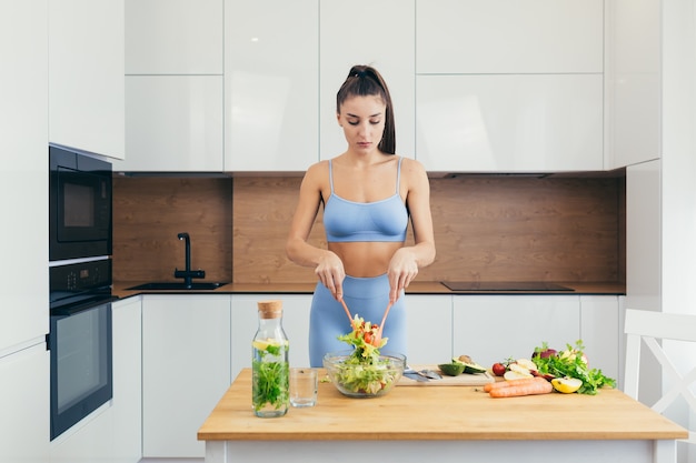 sexy girl, sportswoman prepares salad at home