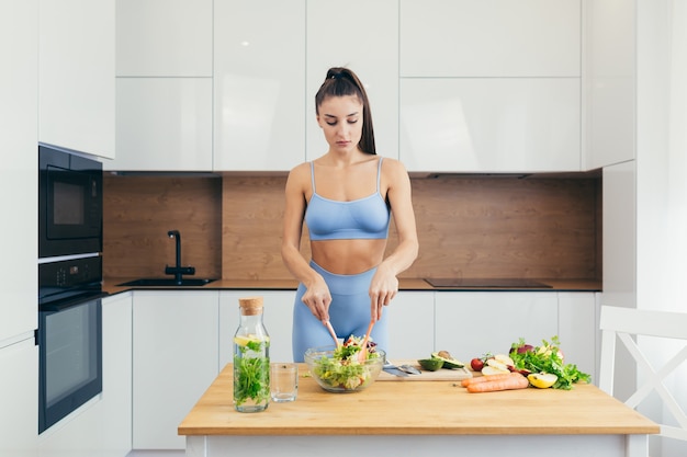 sexy girl, sportswoman prepares salad at home