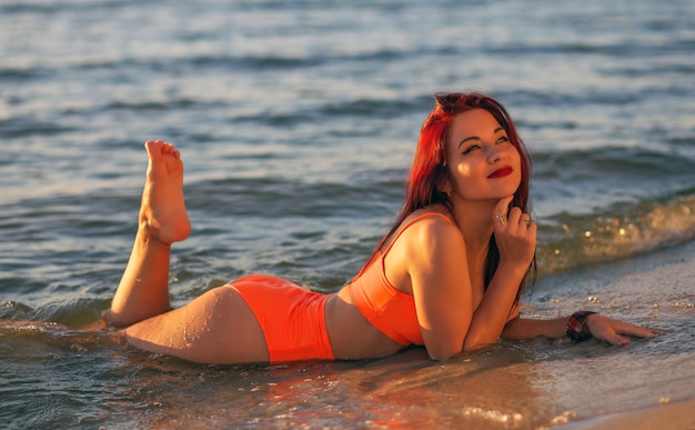 Sexy girl in swimsuit posing on the beach at sunset