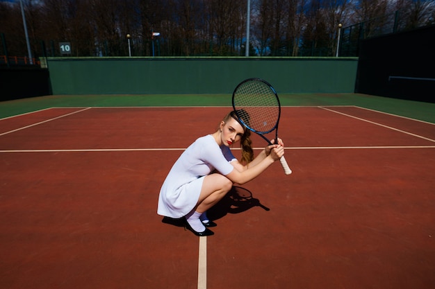 Sexy girl tennis player holding tennis racket on the court. Young woman is playing tennis.