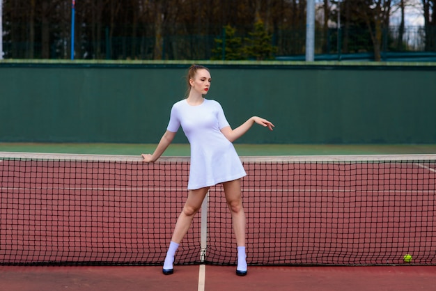 Foto racchetta di tennis sexy della tenuta del tennis della ragazza sulla corte. la giovane donna sta giocando a tennis.