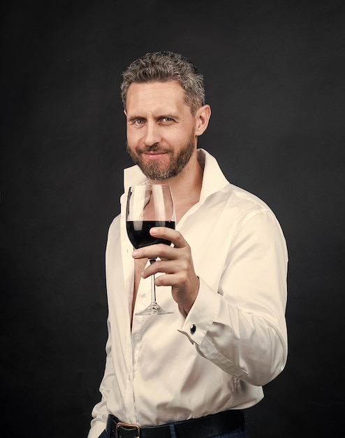 Фото Сексуальный красивый мужчина в белой рубашке держит бокал красного вина на любовном свидании