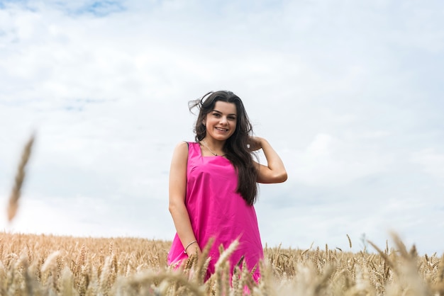 セクシーな幸せなスリムな女性は、小麦畑で夏に歩きます。田舎で娯楽を楽しんでいる女性