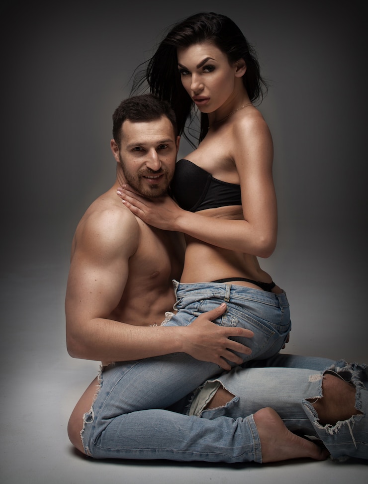 Foto sexy jong koppel. mooie sexy paar verliefd op grijze achtergrond gekleed in spijkerbroek.