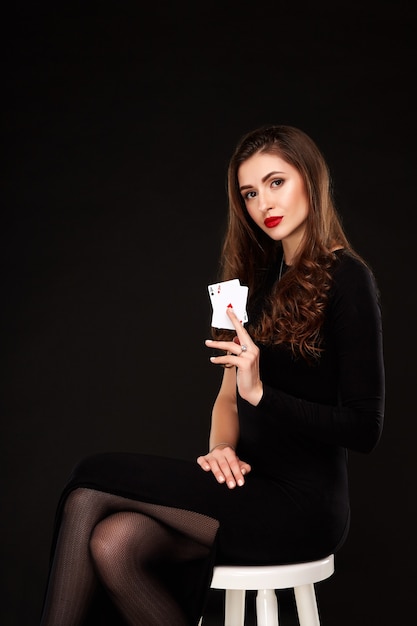 Sexy krullend haar brunette poseren met twee azen kaarten in haar handen poker concept isolatie op witte ba...