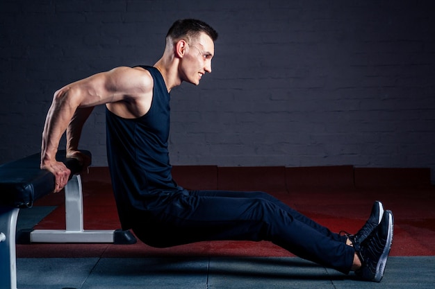 Sexy man exercising on simulators on a dark background