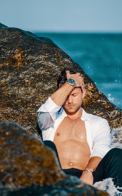 Sexy man in wet shirt on beach