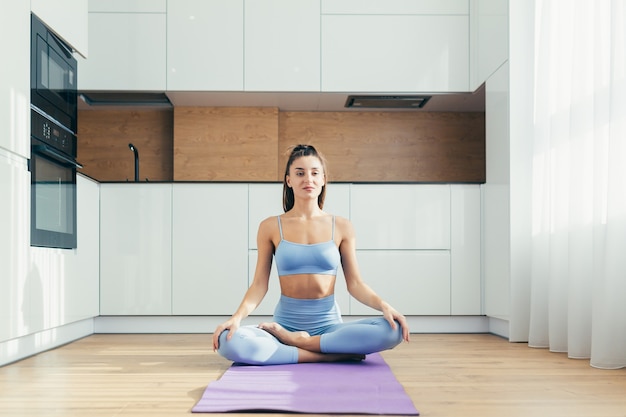 Sexy meisje doet yoga thuis in de keuken