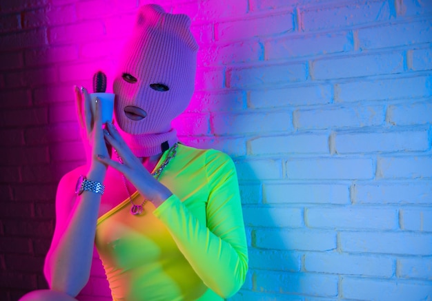 Sexy meisje in een bodysuit in een roze masker op een neon achtergrond met een cactus op een feestje