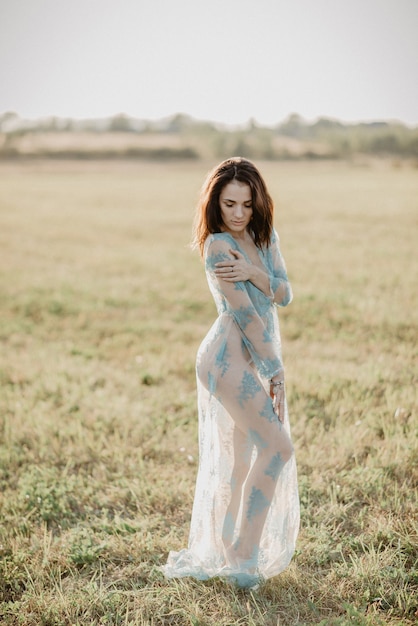 Sexy meisje in ondergoed topless poseren in een veld in de zomer buiten. Het effect van een kleine filmkorrel toegevoegd