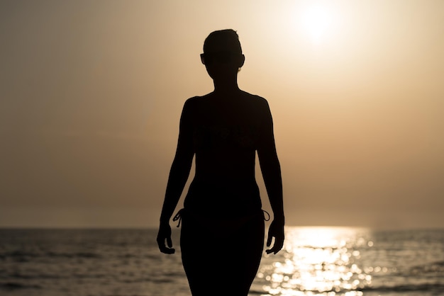 Sexy meisje silhouet op het strand bij zonsondergang boven de zee ruimte tekst kopiëren