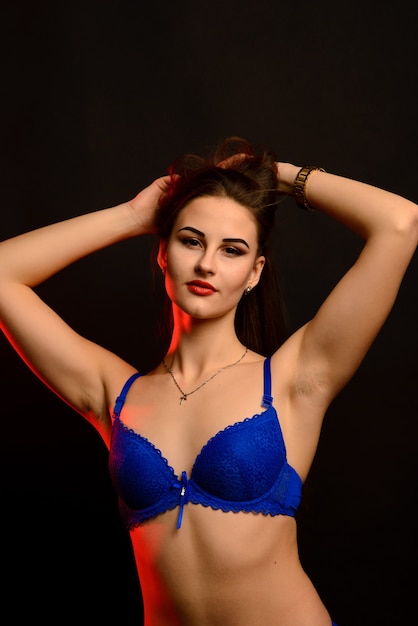 Sexy mode brunette vrouw met lang donker haar in blauwe lingerie op zwart