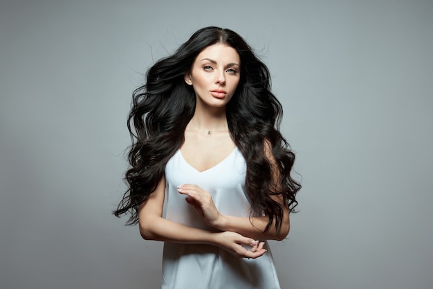 Sexy mode vrouw met lang haar, sterk krullend haar van een brunette meisje. Natuurlijke cosmetica voor haarverzorging, sterke wortels