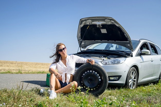 Sexy mooie vrouw en kapotte auto op de weg. Road trip problemen