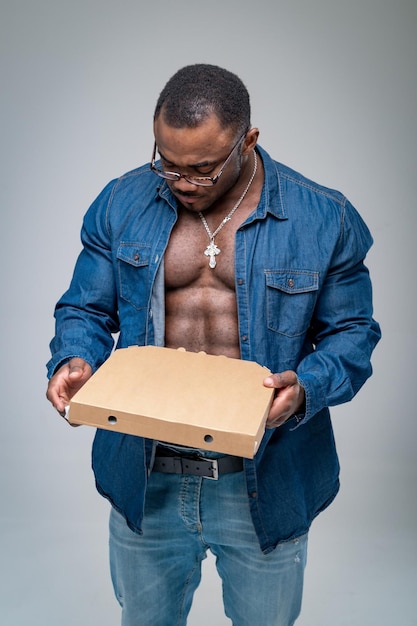 Sexy muscular courier with pizza box Stylish handsome man posing with pizza for camera