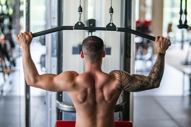 Sexy muscular man pumps his muscles and lifts dumbbells in gym strong fit man exercising with dumbbe