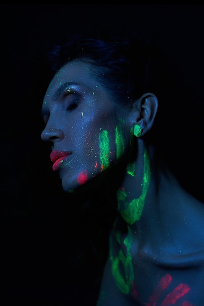 Sexy Nude woman in neon light, UV paint on the woman face and body