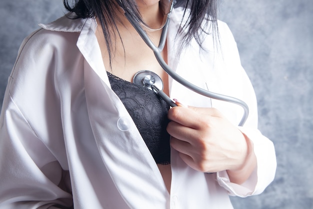 Sexy nurse in bra listening to her heartbeat with stethoscope  