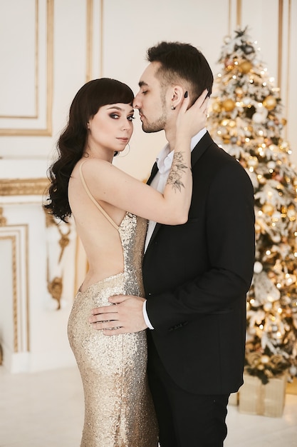 Sexy passionate couple celebrating christmas together attractive woman in gold evening dress and han...