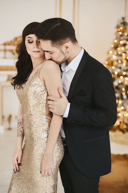 Sexy passionate couple celebrating christmas together attractive woman in gold evening dress and han...