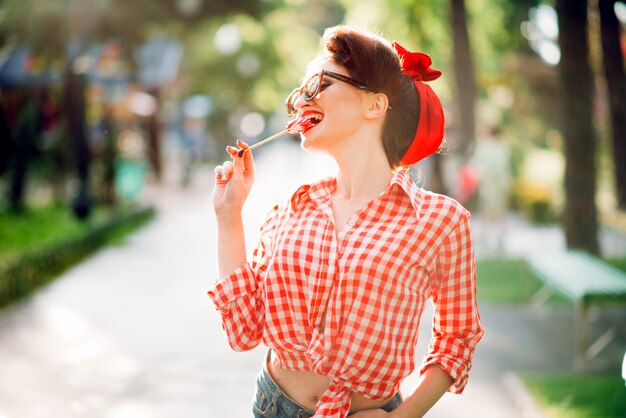 Sexy pin up girl with lollipop walks in a park