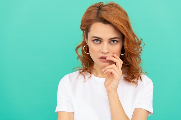 Sexy redhead girl with curly hair has perfect skin on blue background copy space skincare